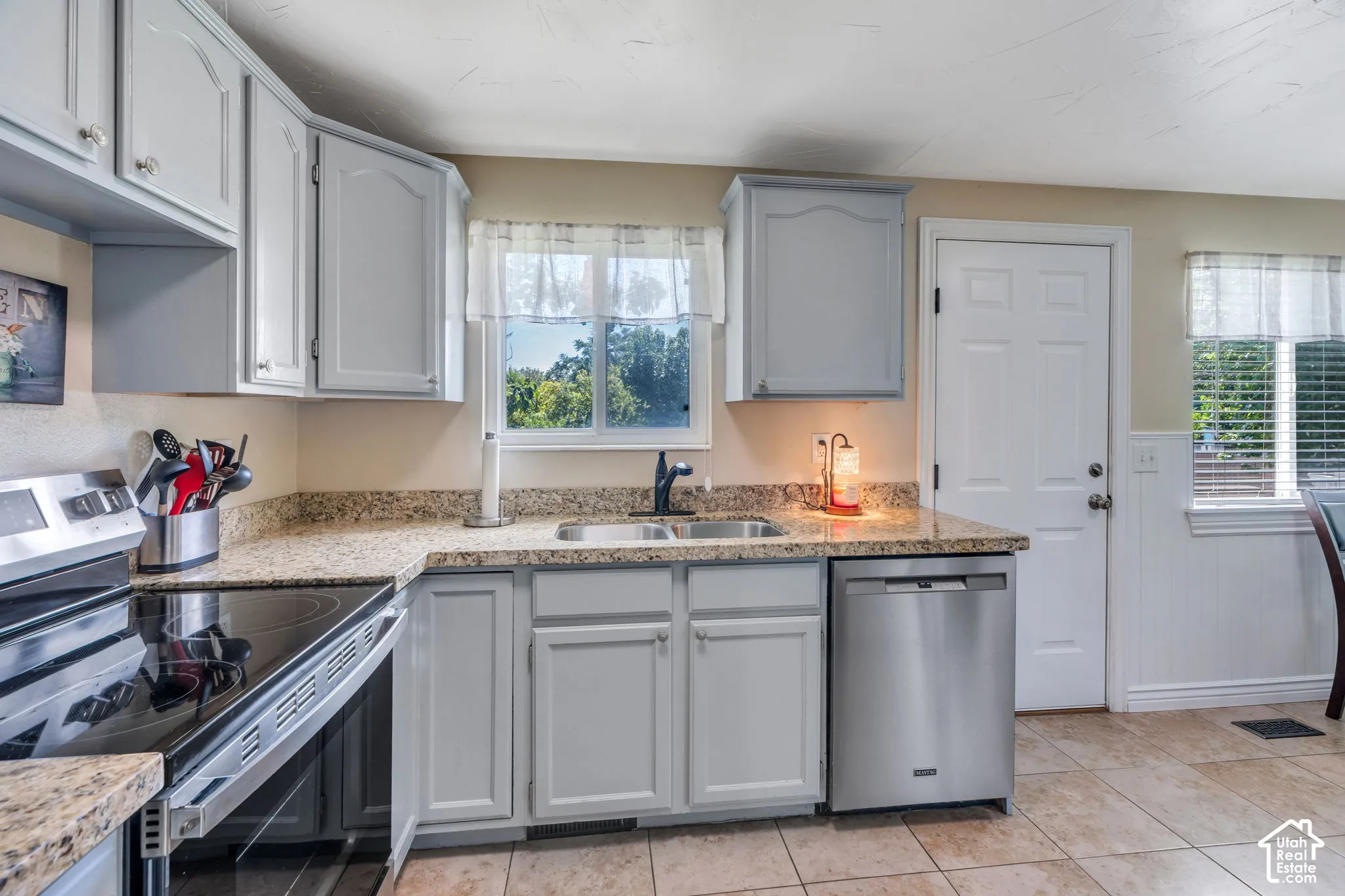 Refreshed kitchen features stylish gray cabinetry, granite countertops and a newer flat-top range for a clean, updated look.