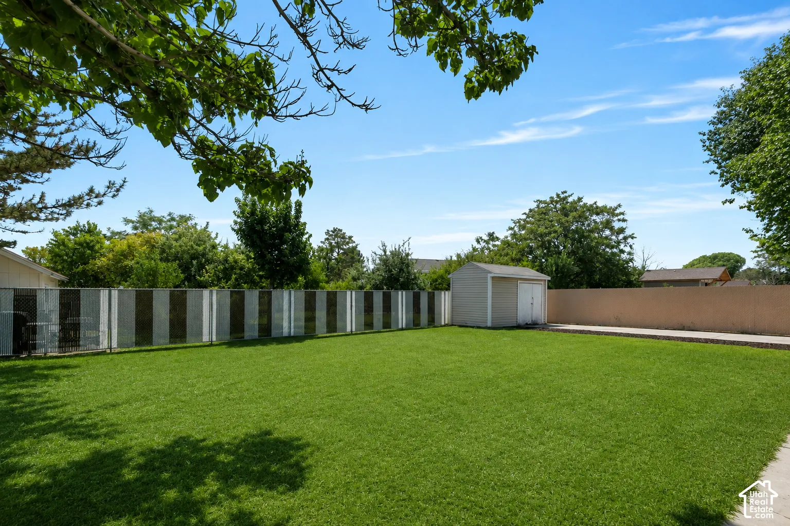 Expansive, fully fenced backyard with mature trees, a private setting, plenty of green space, and a detached shed/garage for extra storage.