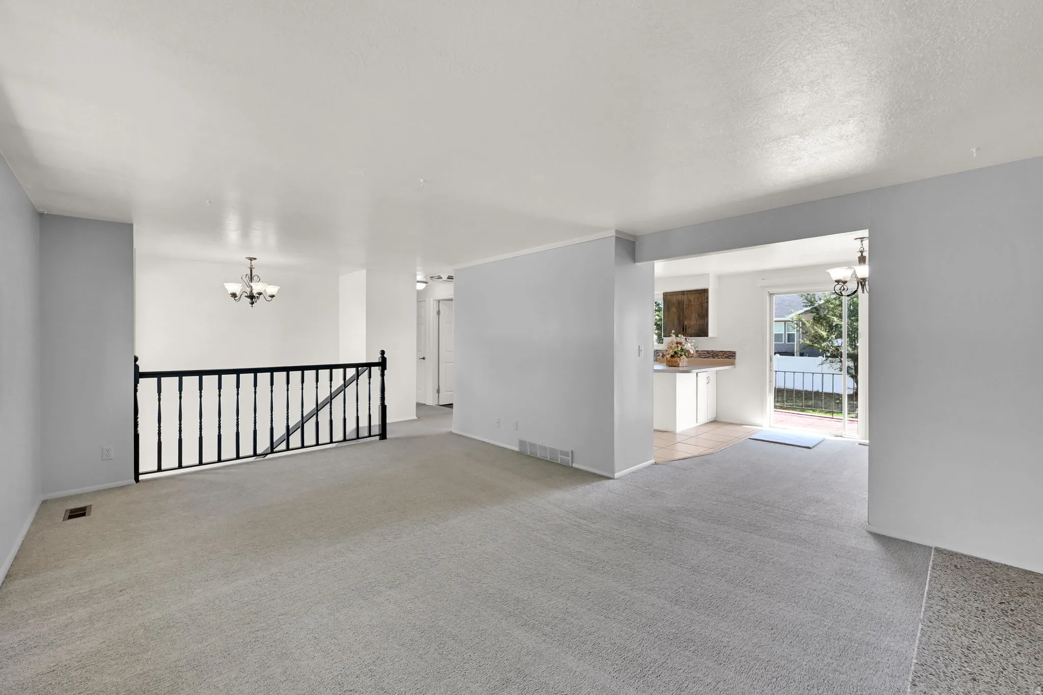 Light gray wall paint, light-toned carpeting, white ceilings, and an open entryway to a separate room with tiled flooring