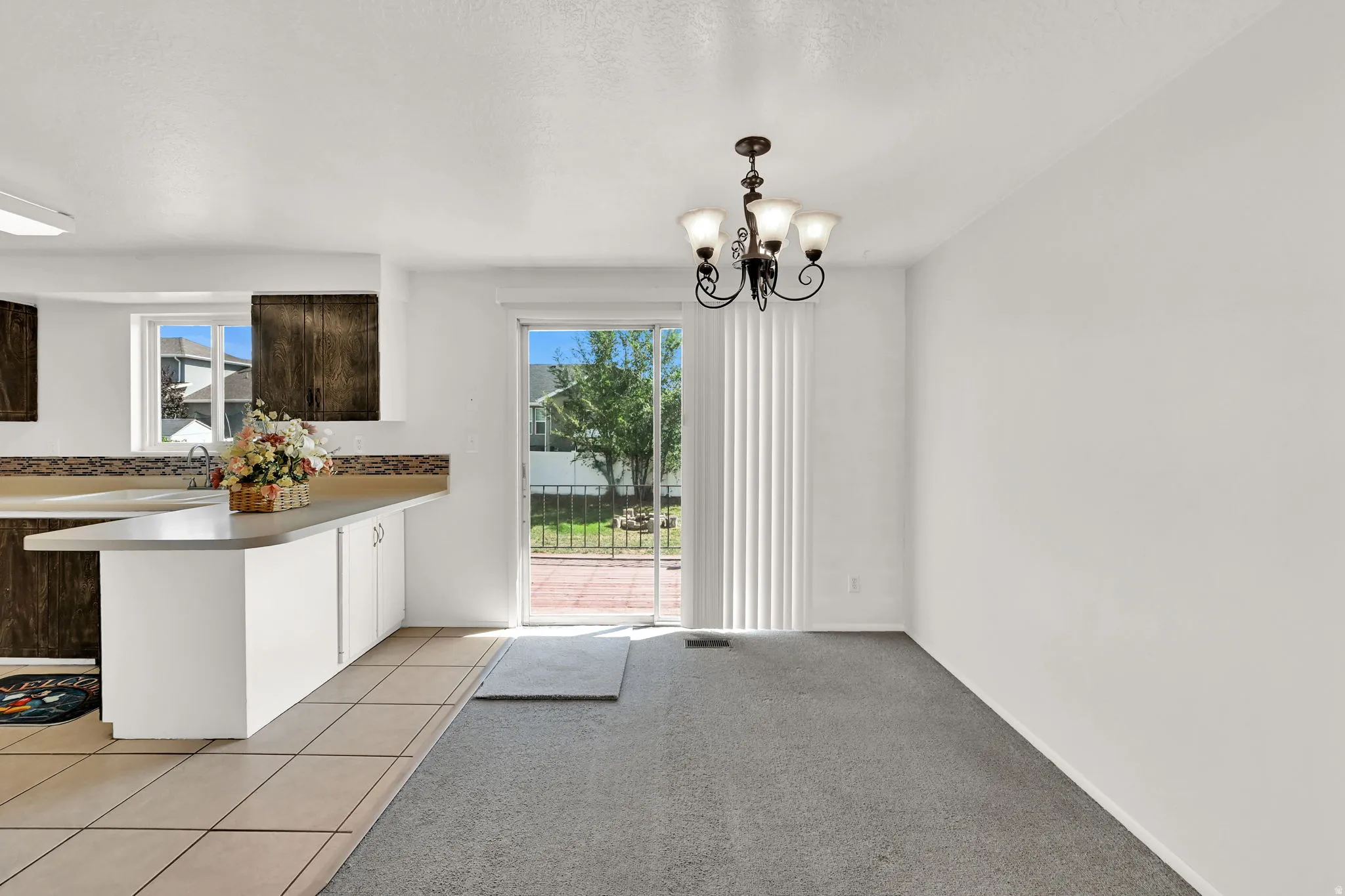 Sliding glass door leading to exterior, tile flooring, carpeted area, and built-in cabinetry with a countertop