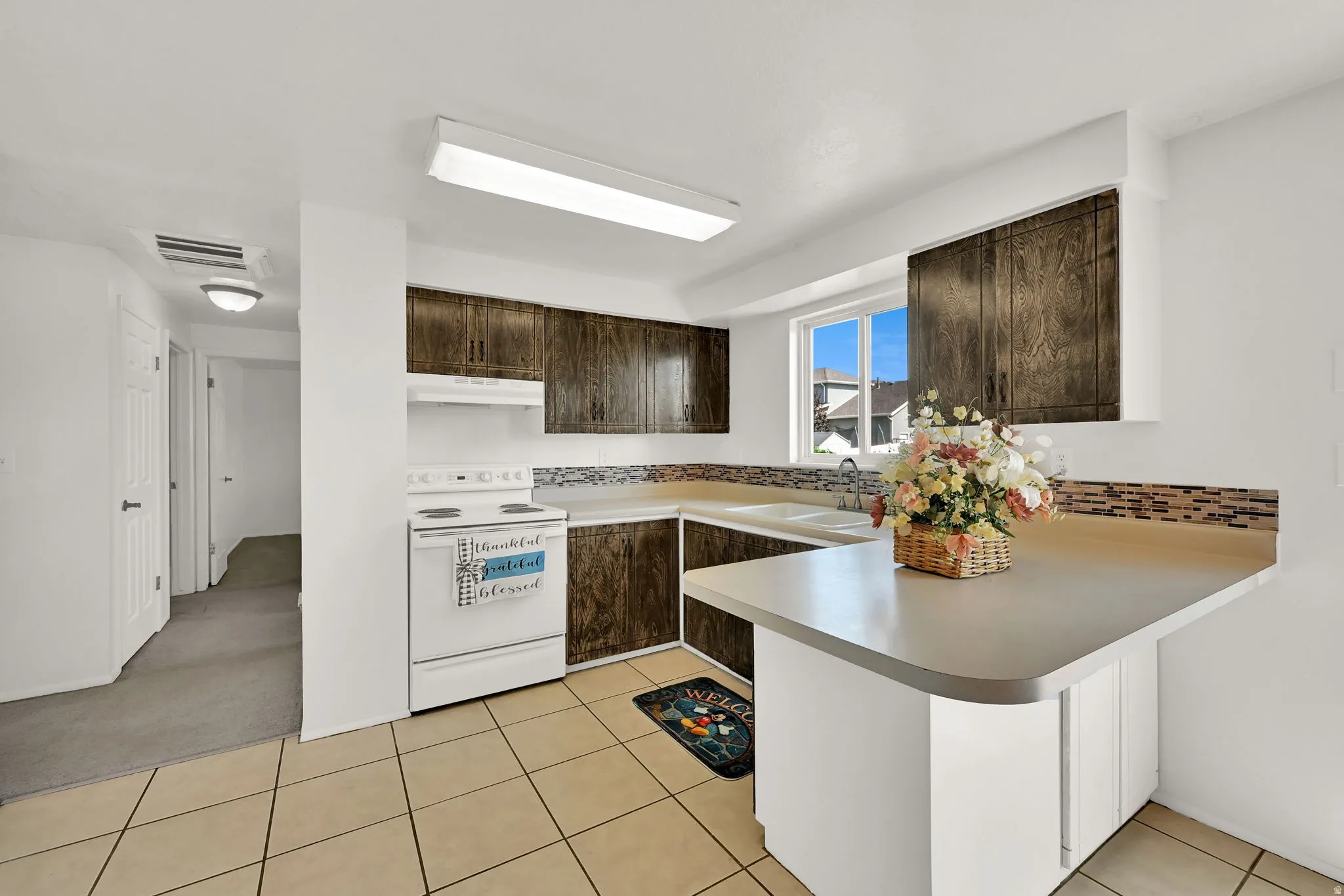 Kitchen featuring wood-finish cabinetry, tile backsplash, laminate countertops, and tile flooring