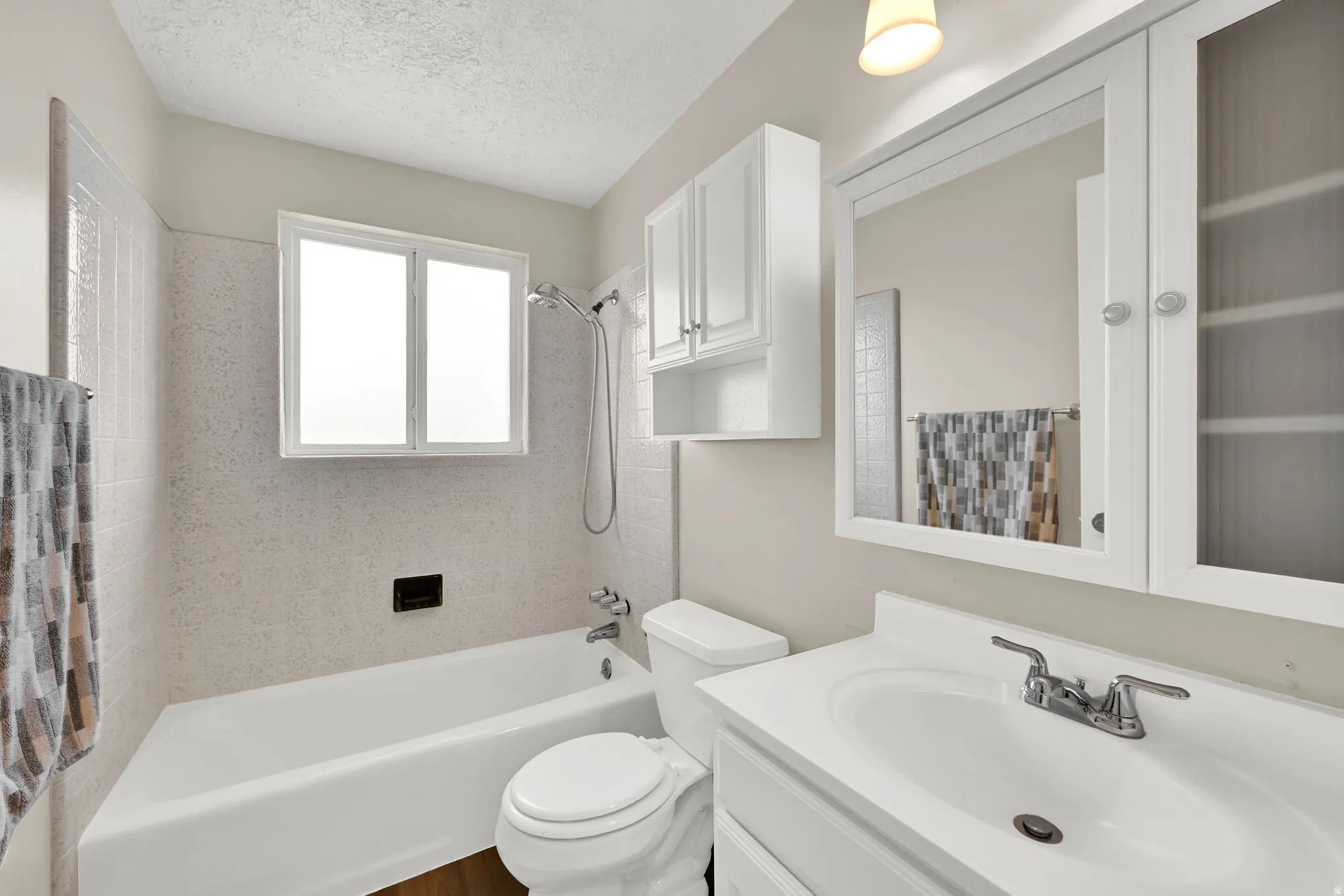 Bathroom featuring a built-in tub with a shower fixture, a single vanity with a white countertop, and a mirrored medicine cabinet