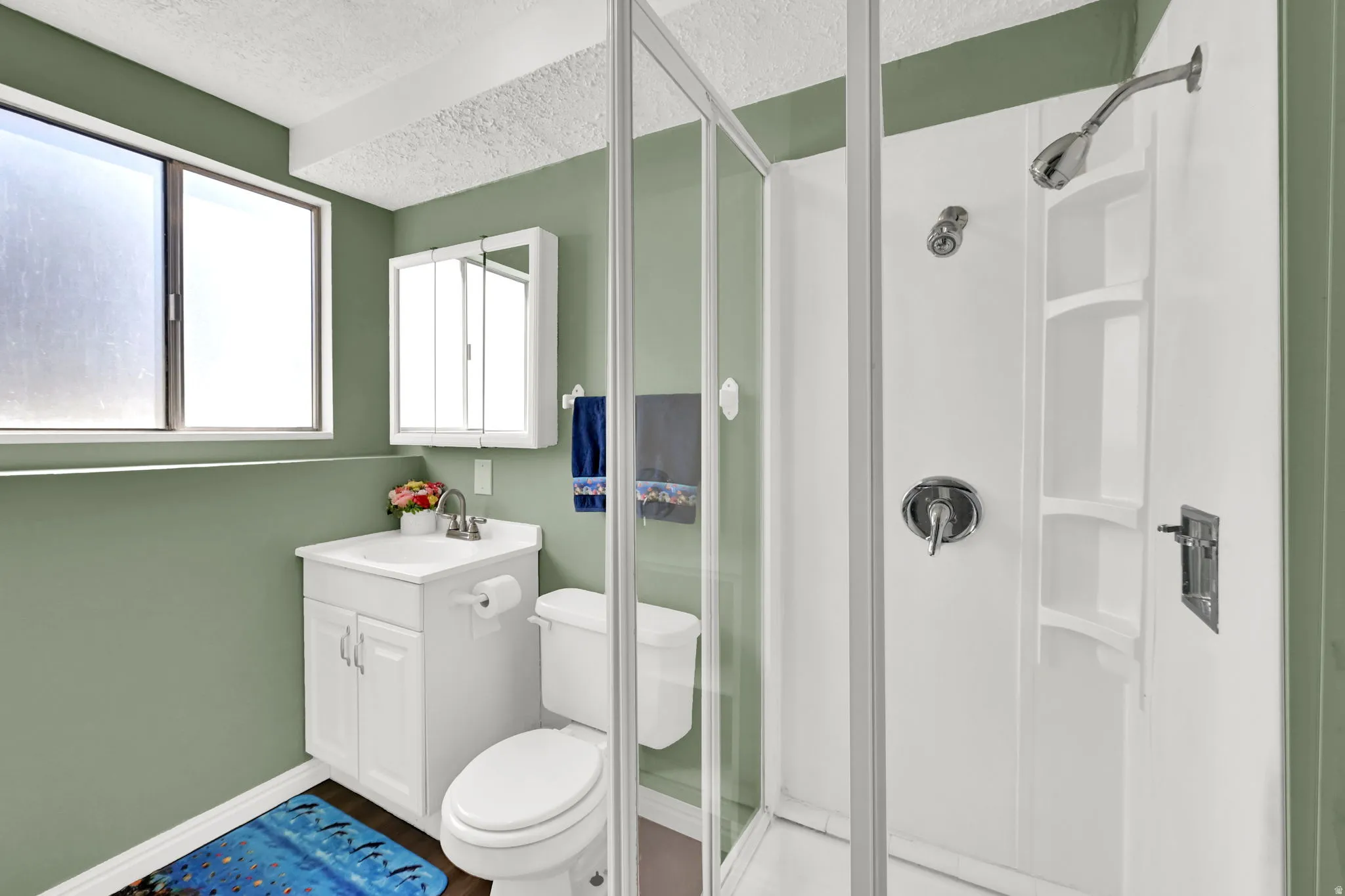 Compact bathroom featuring a white vanity with integrated sink, chrome faucet, and a wall-mounted medicine cabinet