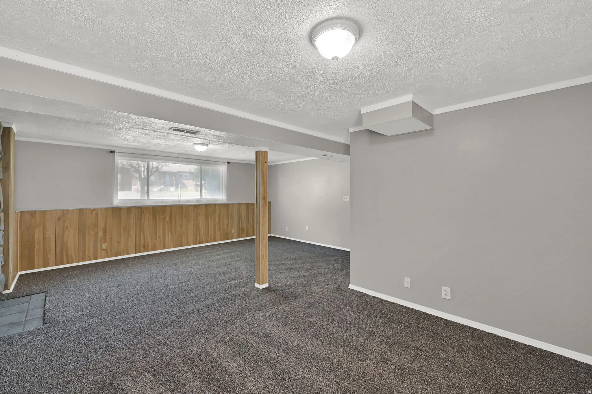 Carpeted flooring, wood-panel wall accents, recessed lighting, and a large window