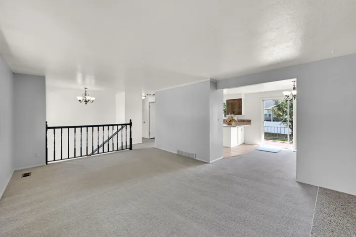 Light gray wall paint, light-toned carpeting, white ceilings, and an open entryway to a separate room with tiled flooring