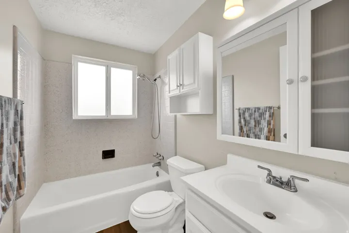 Bathroom featuring a built-in tub with a shower fixture, a single vanity with a white countertop, and a mirrored medicine cabinet