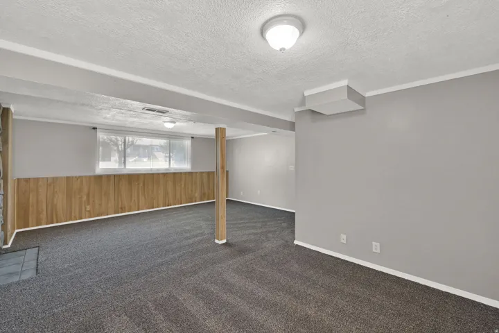 Carpeted flooring, wood-panel wall accents, recessed lighting, and a large window