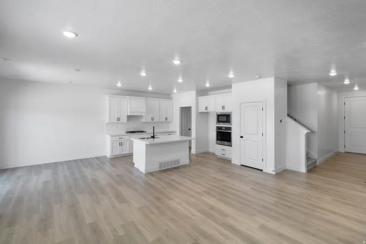 Open-concept main level featuring wood-finish flooring, recessed lighting, and a white kitchen with shaker cabinetry