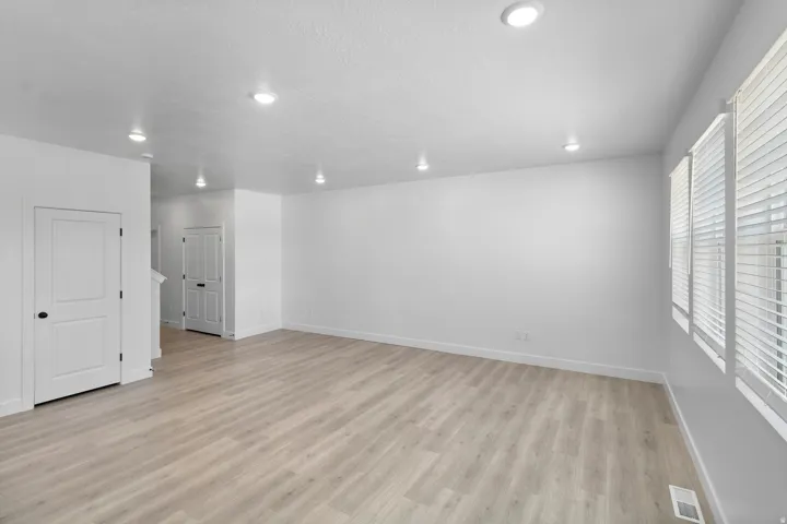 Recessed lighting, wood-finish flooring, multiple windows with horizontal blinds, and a neutral color palette