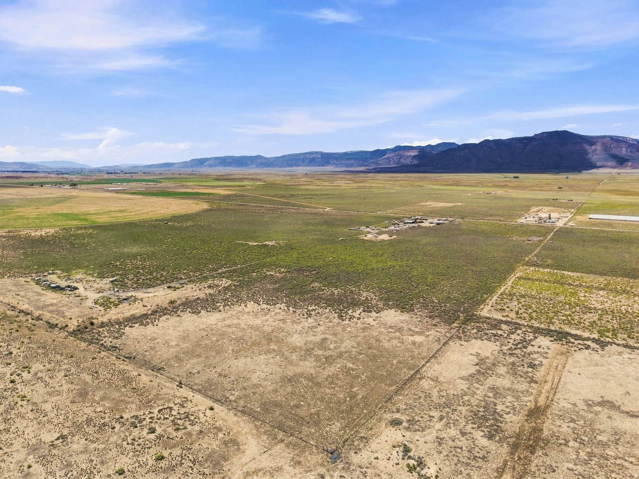 Expansive open land with varied vegetation and distant mountain ranges