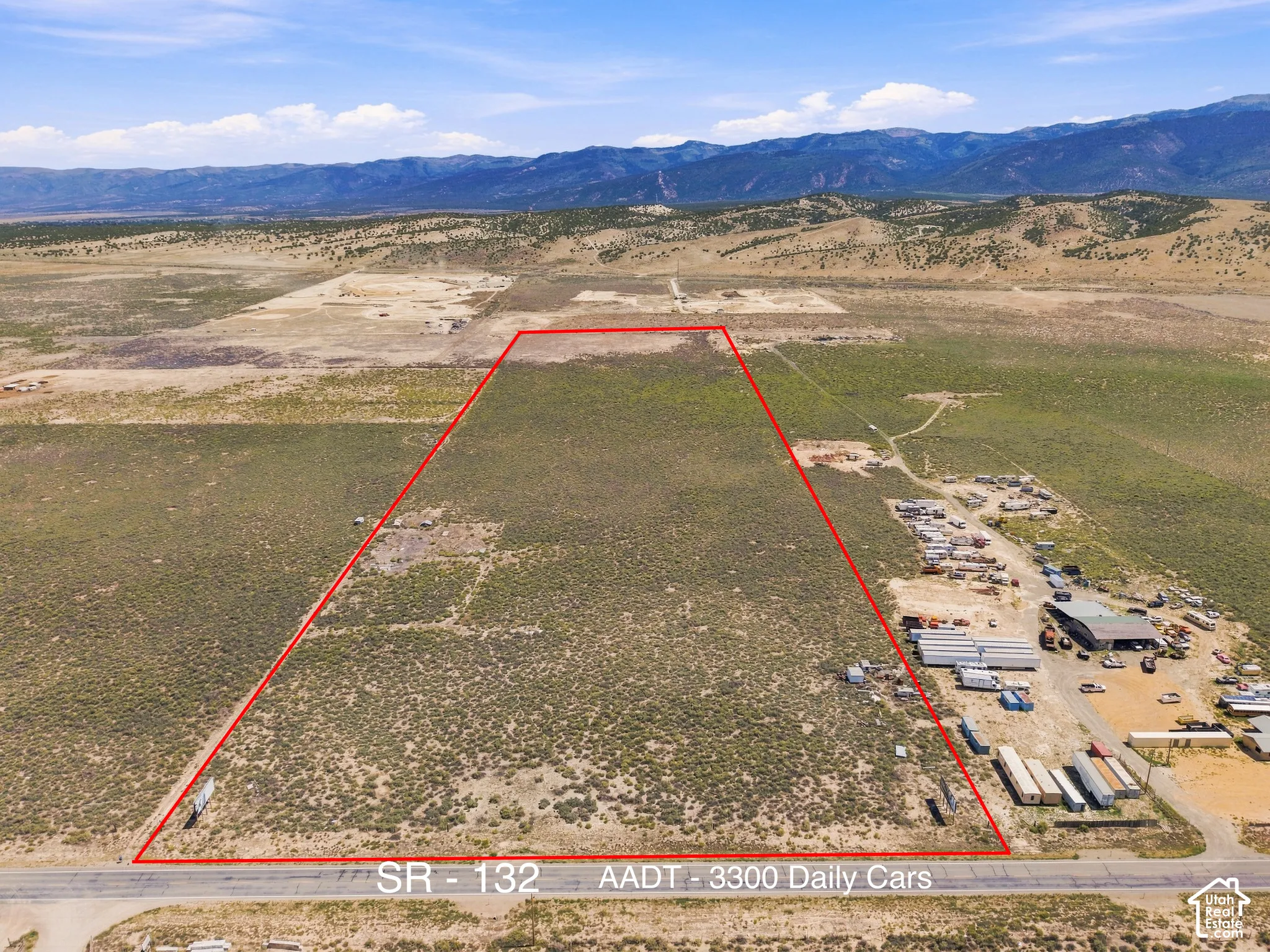 Expansive undeveloped land featuring a clear property boundary, direct road access to SR-132, and a distant mountain backdrop