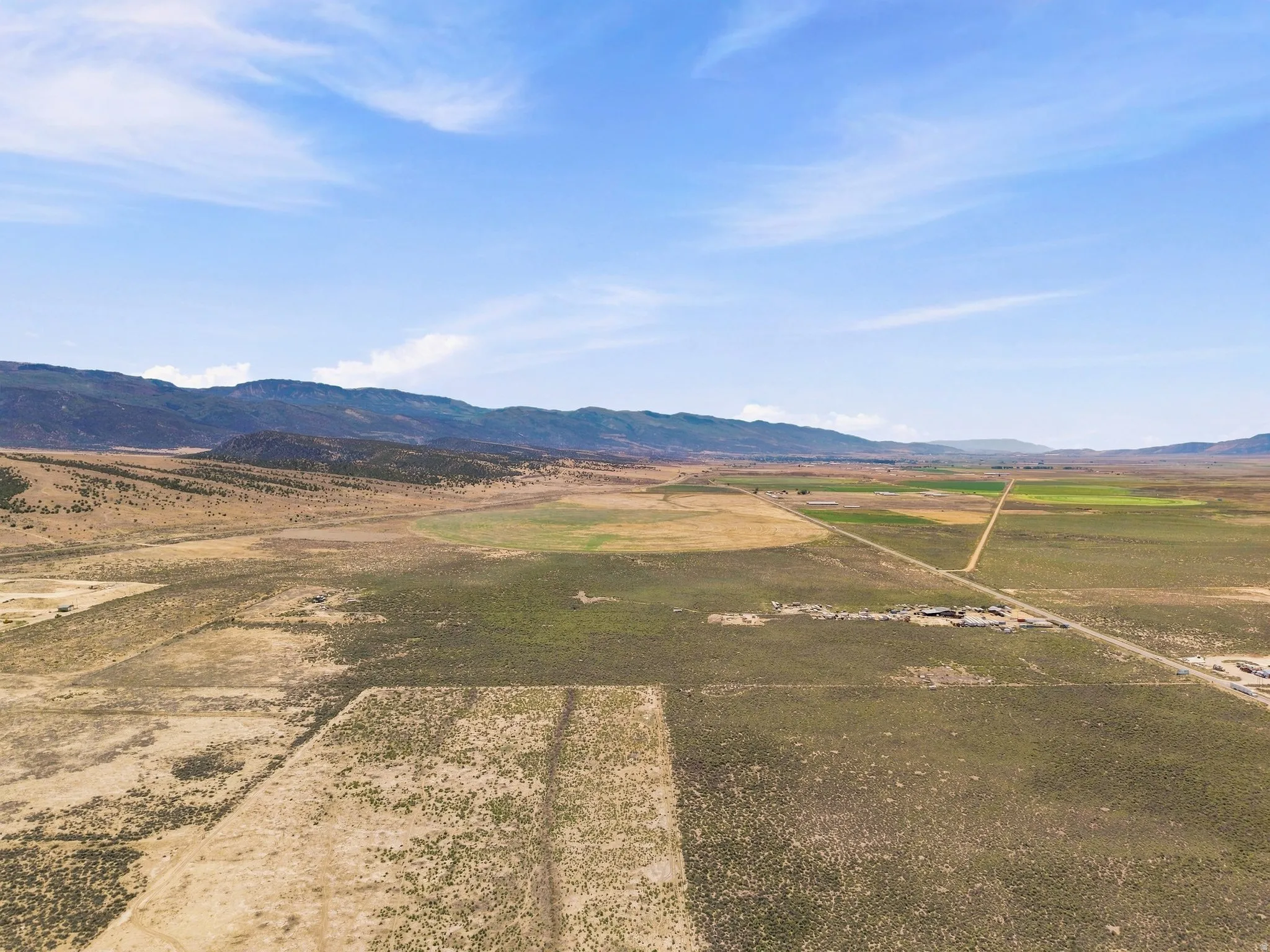 Expansive rural landscape featuring a distant mountain range, varied terrain, and visible agricultural fields