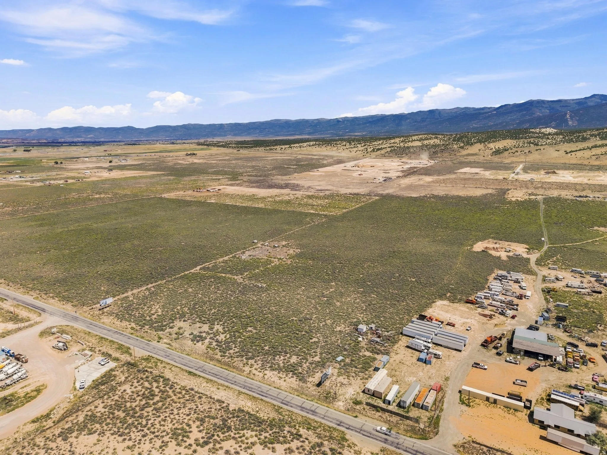 Expansive rural acreage featuring a paved road frontage, natural landscaping, and distant mountain ranges