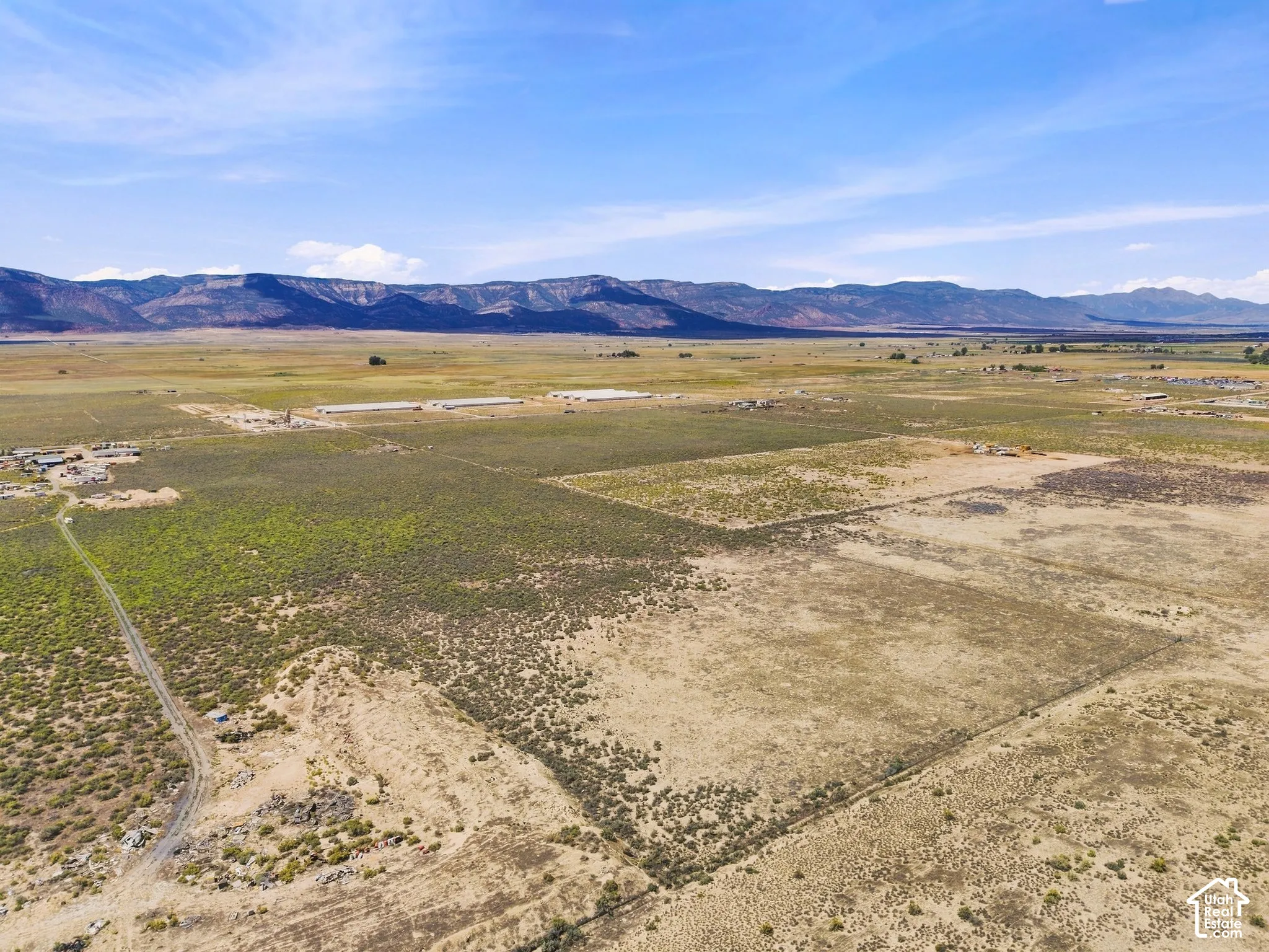 Expansive open land with distant mountain ranges and scattered structures
