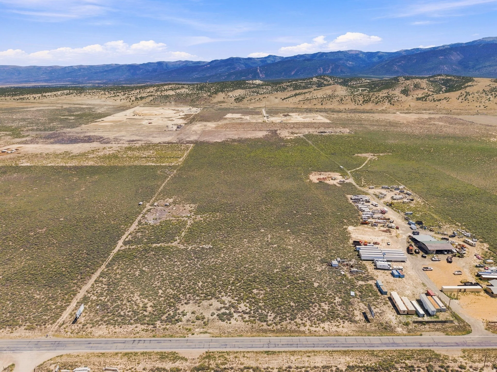 Expansive undeveloped land with visible utility lines and mountain backdrop