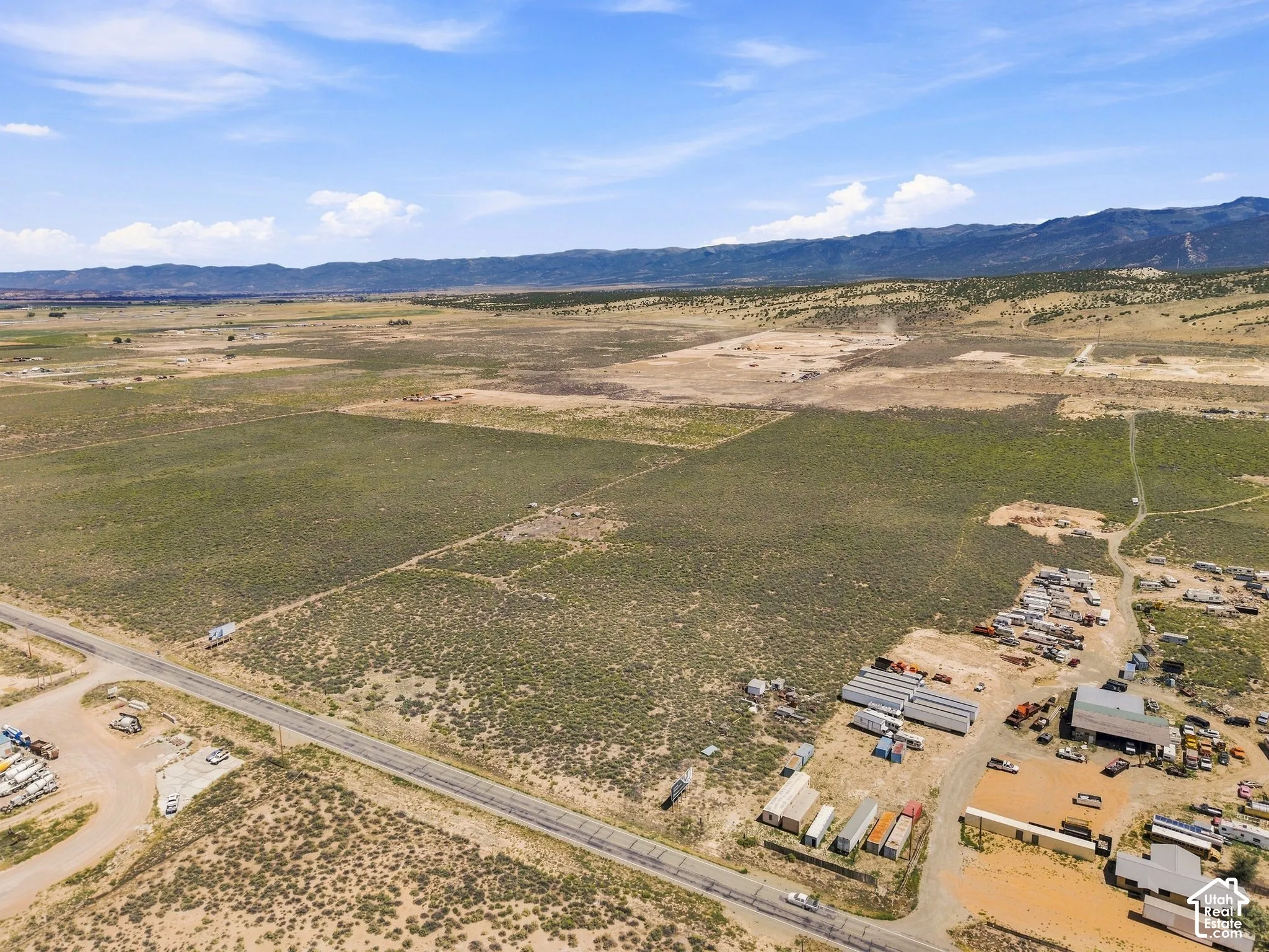 Expansive rural acreage featuring a paved road frontage, natural landscaping, and distant mountain ranges