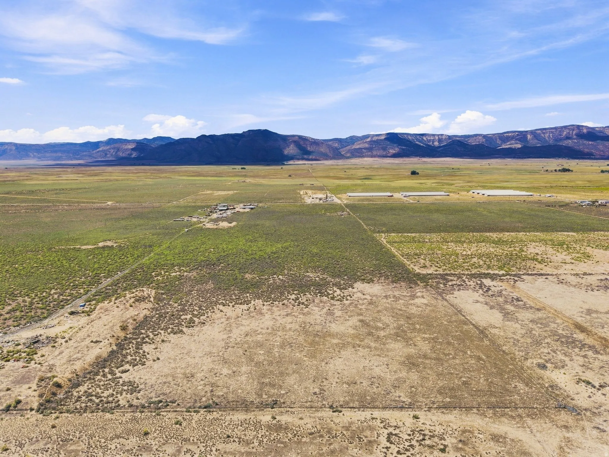 Expansive rural property featuring varied vegetation and distant mountain ranges