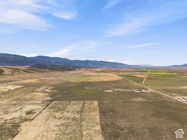Expansive rural landscape featuring a distant mountain range, varied terrain, and visible agricultural fields