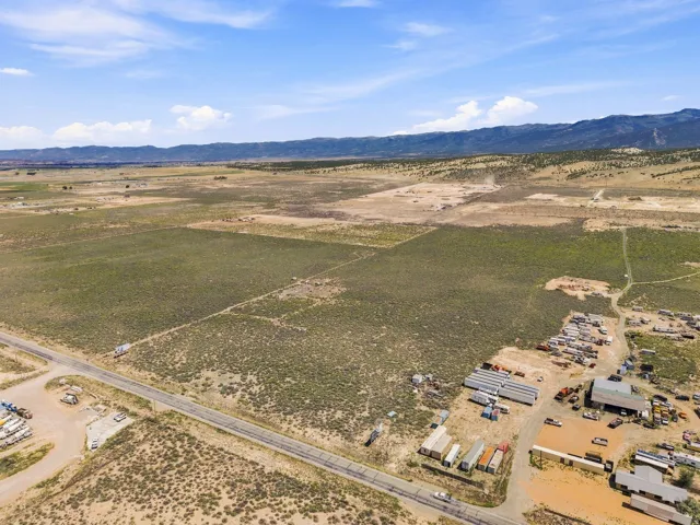Expansive rural acreage featuring a paved road frontage, natural landscaping, and distant mountain ranges