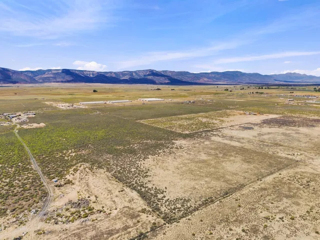 Expansive open land with distant mountain ranges and scattered structures
