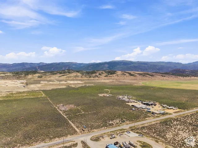 Expansive rural landscape featuring a paved road, scattered buildings, and distant mountains