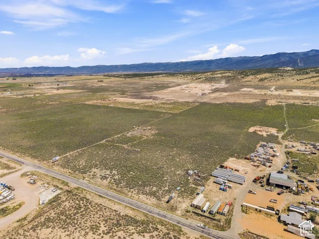 Expansive rural acreage featuring a paved road frontage, natural landscaping, and distant mountain ranges