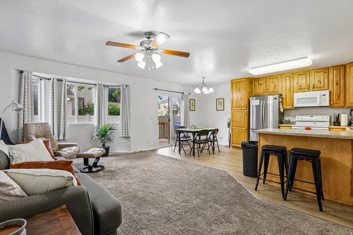 Bright living area with a bay window, ceiling fan, and carpet flooring