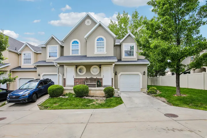 Stucco exterior with brick accents, arched windows, and white garage doors