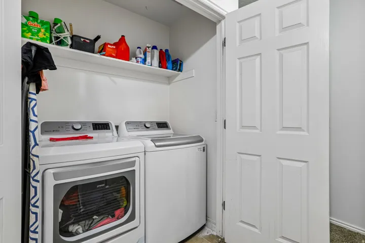 Laundry area featuring a top-load washer and front-load dryer, with an upper storage shelf