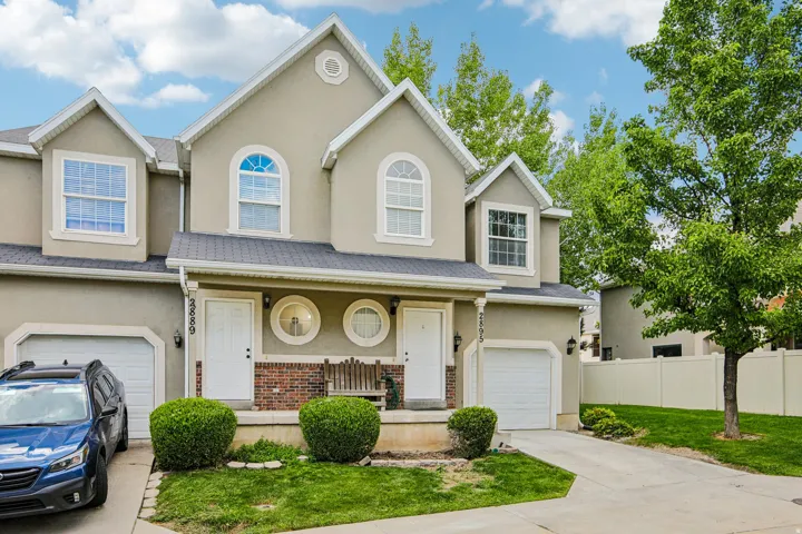 Stucco exterior with brick accent, arched windows, covered porch, and attached garage