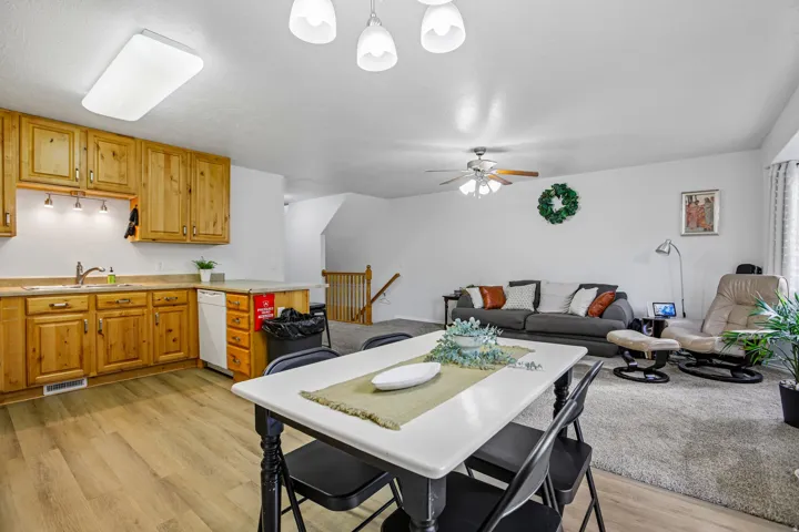 Open concept living area with wood-finish flooring, light wood cabinetry, and a ceiling fan