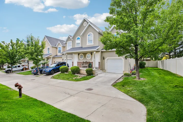 Stucco exterior with arched windows, an attached single-car garage, concrete driveway, and a fenced backyard with a mature tree