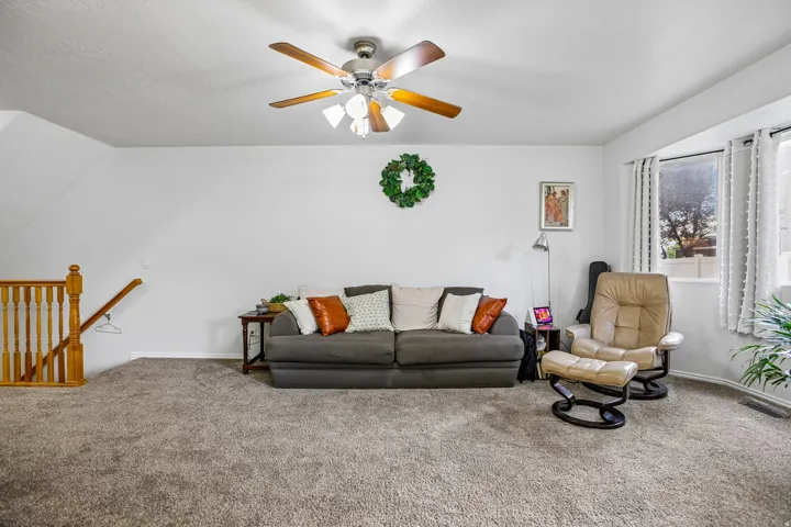 Recessed lighting, ceiling fan with integrated lighting, wood-finish railing, bay window, and carpeted flooring