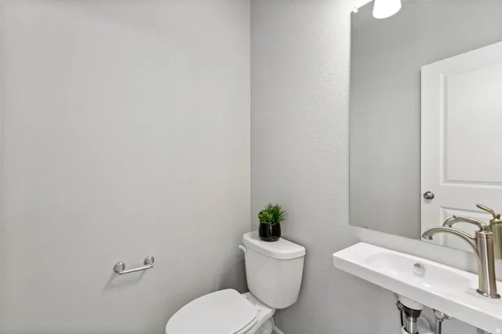 Wall-mounted sink with a brushed nickel faucet, full-height mirror, and a white toilet