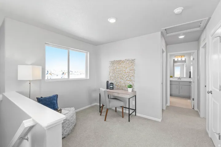 Light-filled upper level with neutral carpeting, white interior doors, and a window with a white frame