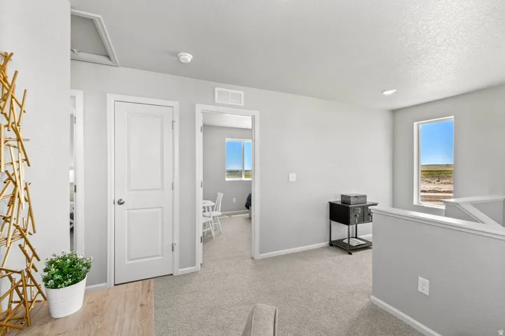 Light gray wall paint, textured ceiling, light gray carpeting, white interior doors, and white trim