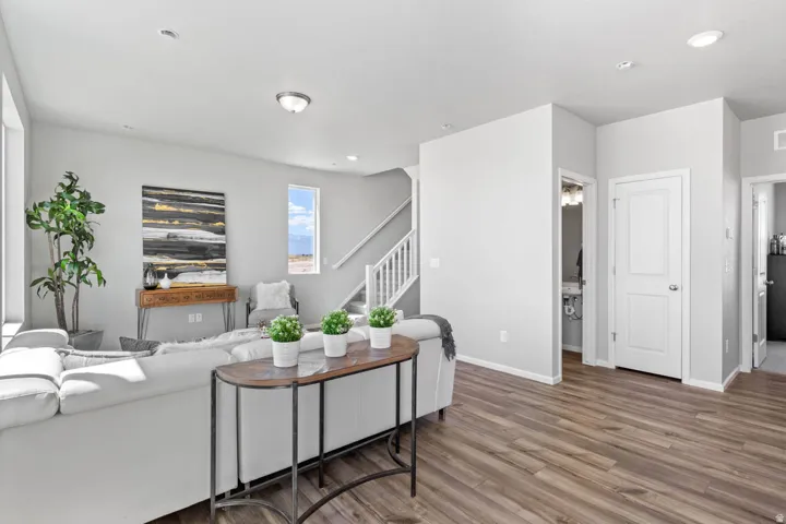 Recessed lighting, wood-finish flooring, white trim, and a staircase with white balusters