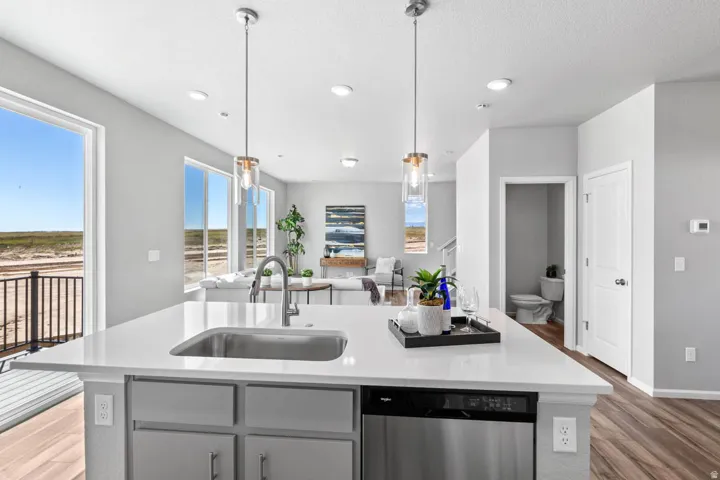 Kitchen island with a stainless steel sink, integrated dishwasher, and pendant lighting