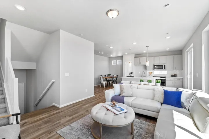 Open-concept living space featuring wood-finish flooring, recessed lighting, and a modern kitchen with light cabinetry