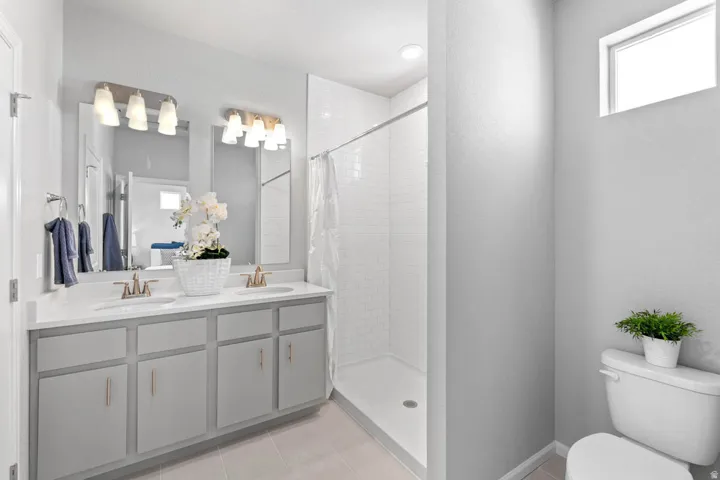 Dual vanity with light gray cabinetry, brushed brass hardware, and undermount sinks