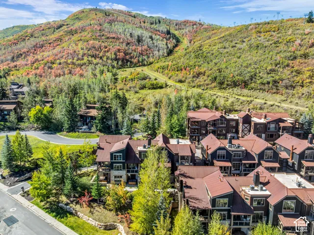 Community of multi-story residences with rich exterior finishes, individual balconies, and a mountain backdrop