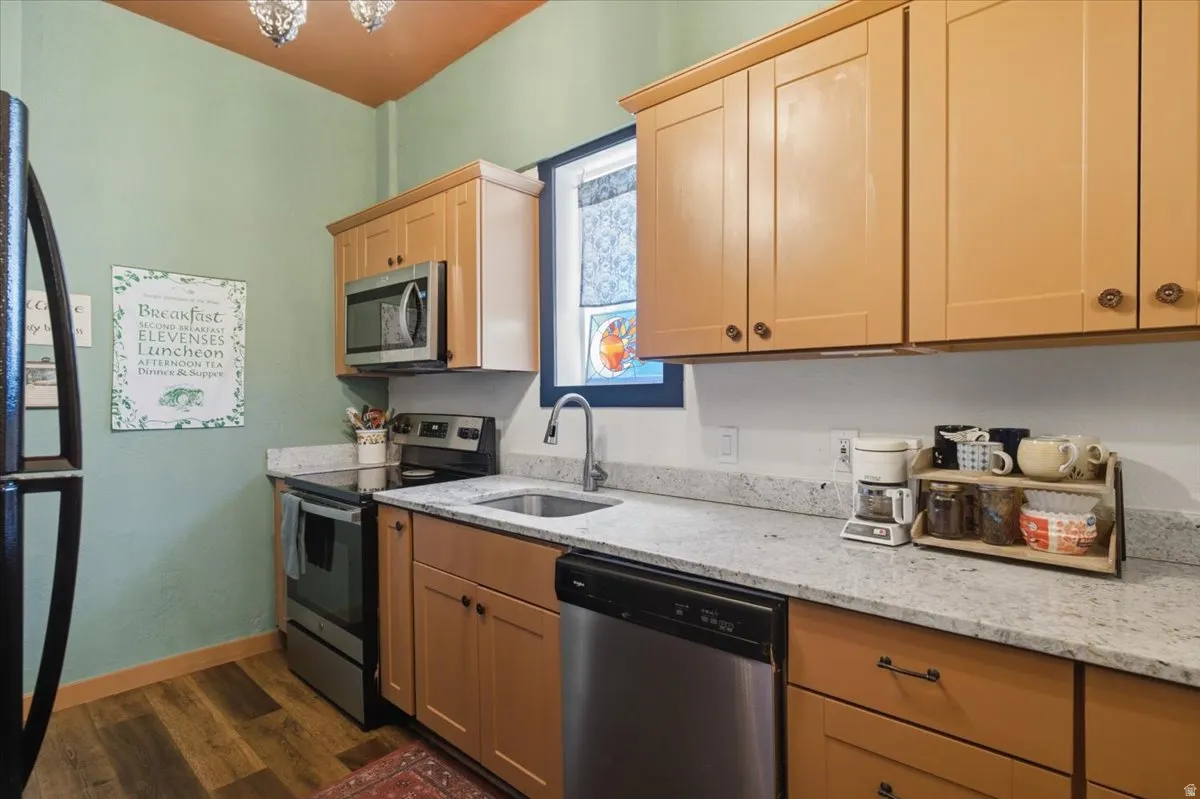 Kitchen featuring wood-finish cabinetry, stainless steel appliances, a stainless steel sink, and light speckled countertops