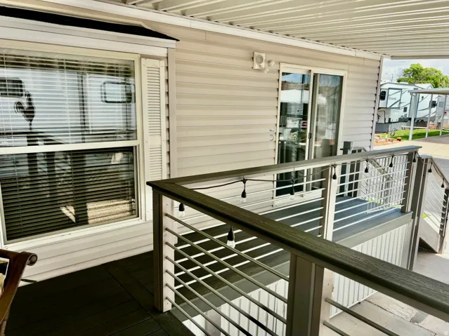 Covered exterior deck with composite flooring, featuring a metal railing system and a sliding glass door