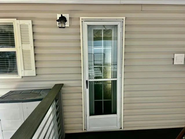 Light-colored horizontal siding with contrasting white window shutters and a black exterior light fixture