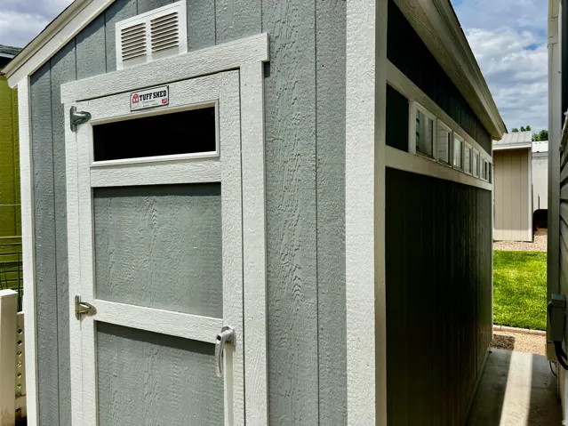 Gable roof storage shed featuring a single entry door, transom window, and a white louvered vent