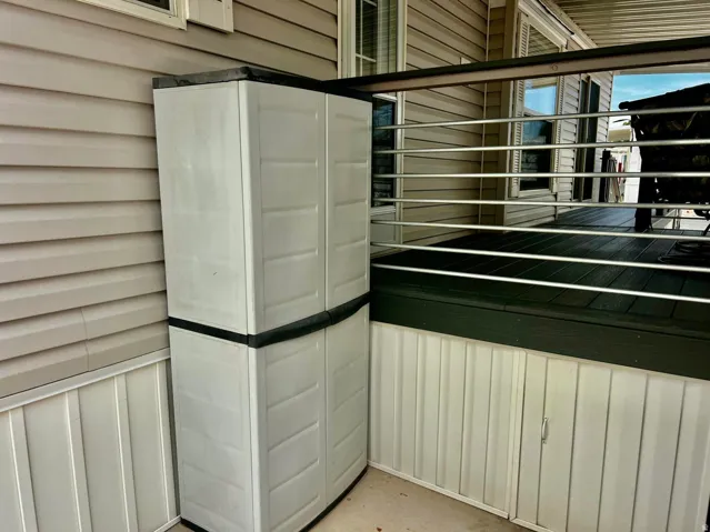 Composite deck with horizontal metal railing, a built-in storage cabinet, and vinyl siding