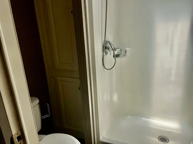 Compact shower stall with chrome-finish fixtures and an integrated soap dish