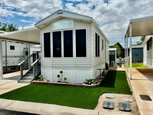 Siding exterior with multiple windows, covered patio, and artificial turf landscaping