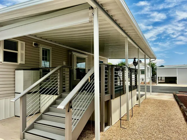 Covered outdoor deck with cable railing and exterior stairs, featuring a gravel pathway