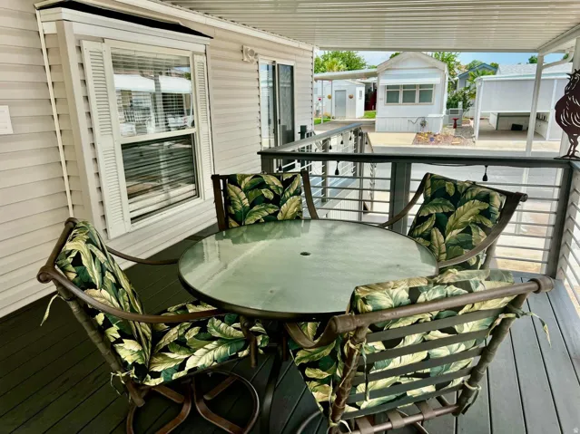 Covered outdoor deck with composite decking, white vinyl siding, and a metal railing system